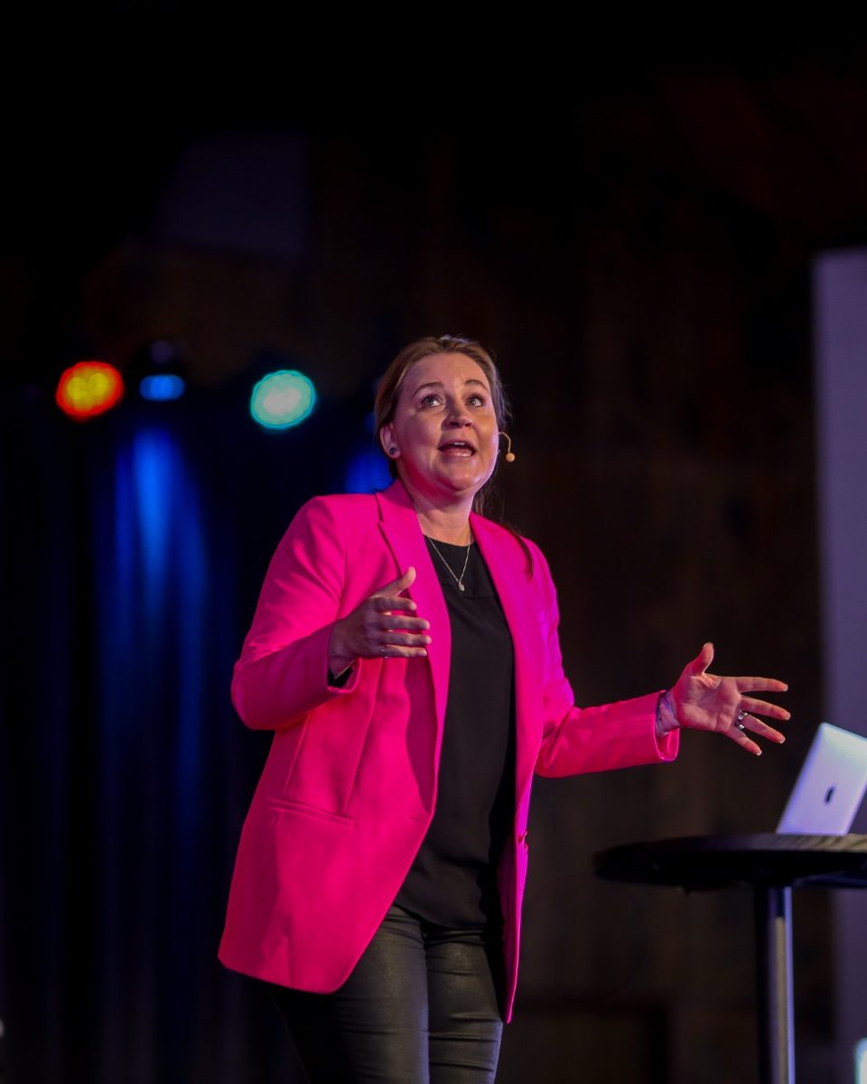 Jen J Kelly speaking on stage at a women's conference