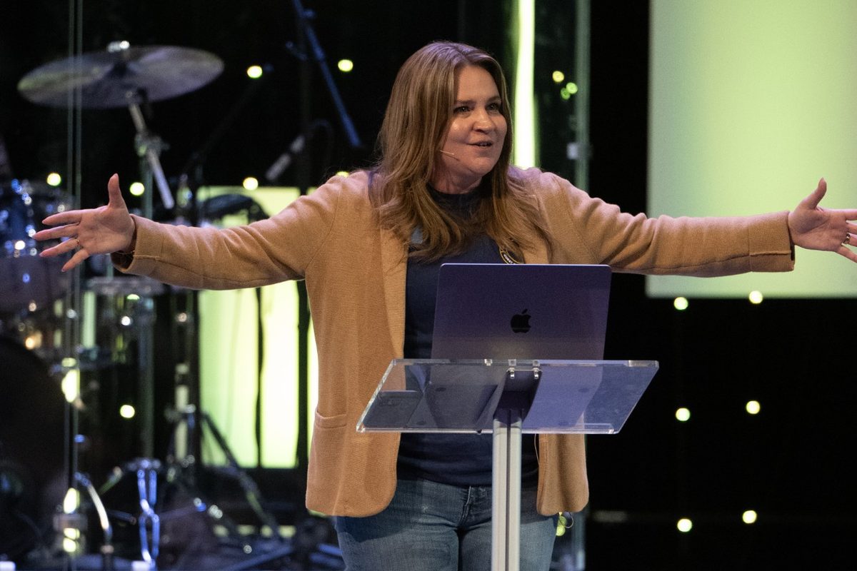 Jen speaking with arms open wide at a conference